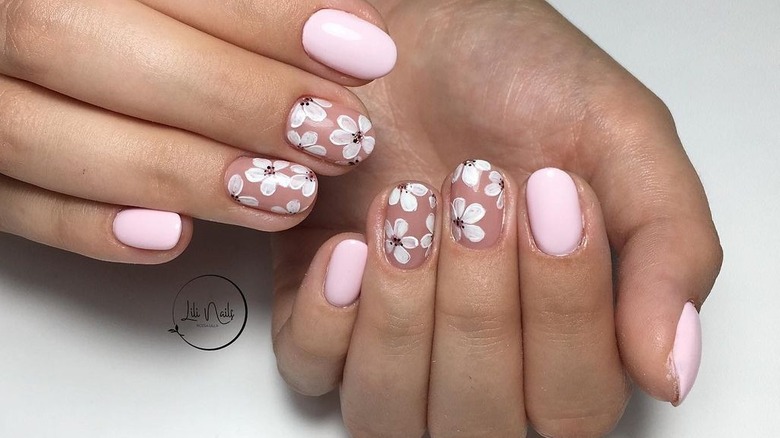 White flowers painted on pink nails